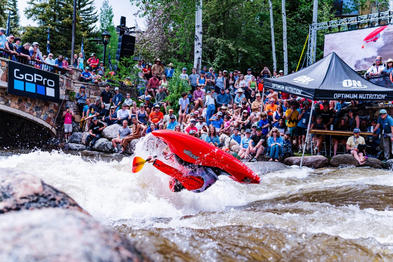 Kayaker does a flip during the 2024 GoPro Mountain Games as fans look on.