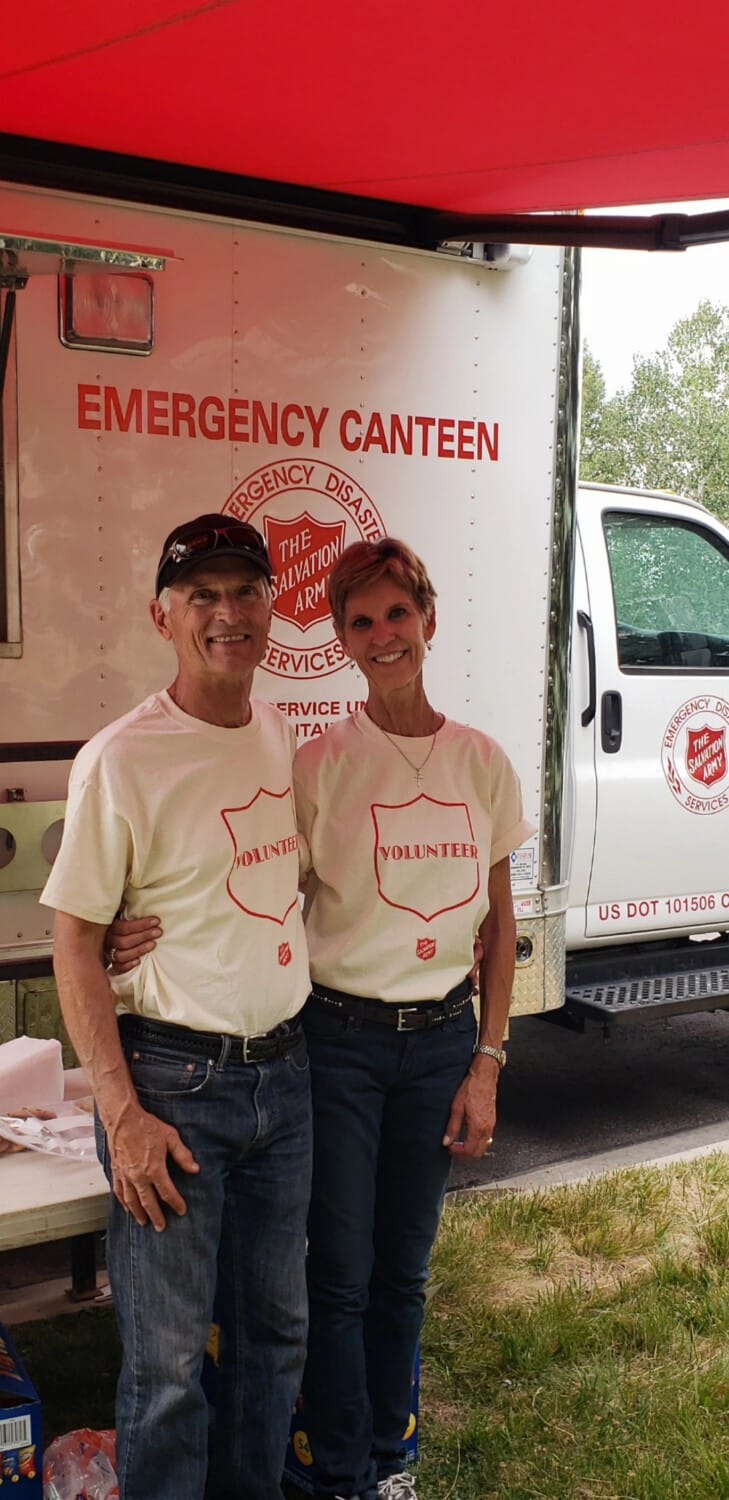 Debby and Harry Jasper smile in front of an emergency canteen bus while volunteering with the salvation army 